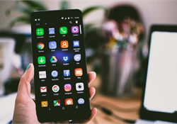 A hand holding a smartphone showing a screen full of app icons